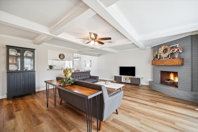 living room featuring beam ceiling, ceiling fan, coffered ceiling, a brick fireplace, and wood-type flooring