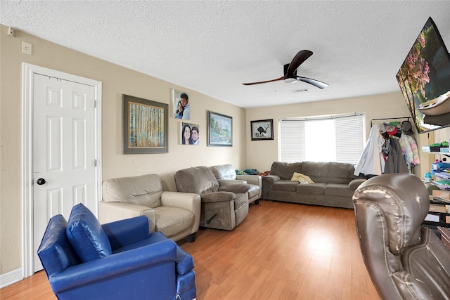 living room featuring hardwood / wood-style flooring, ceiling fan, and a textured ceiling