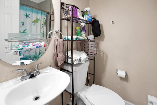 bathroom featuring curtained shower, sink, and toilet