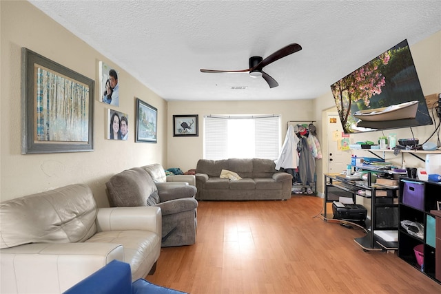 living room featuring ceiling fan, a textured ceiling, and hardwood / wood-style flooring