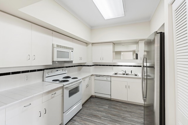 kitchen featuring dark hardwood / wood-style flooring, white appliances, sink, white cabinets, and tile counters