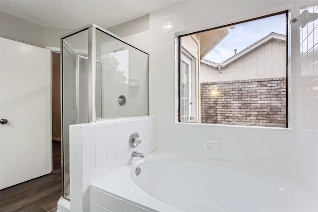 bathroom with wood-type flooring, plus walk in shower, and a skylight