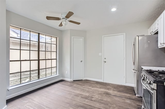 kitchen with white cabinetry, a wealth of natural light, stainless steel range oven, and light hardwood / wood-style flooring