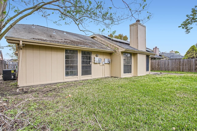 back of property with central AC unit and a lawn