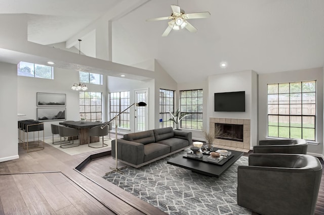 living room featuring plenty of natural light, beam ceiling, a tiled fireplace, and hardwood / wood-style floors