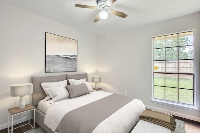 bedroom featuring multiple windows, ceiling fan, hardwood / wood-style flooring, and a textured ceiling