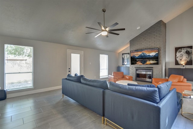 living room with a brick fireplace, ceiling fan, and vaulted ceiling