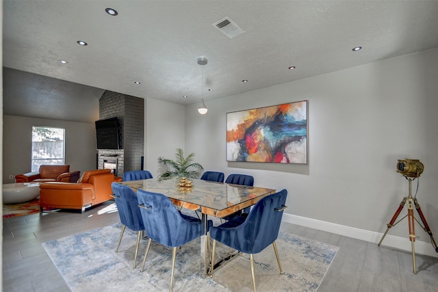 dining room featuring a large fireplace and light hardwood / wood-style floors