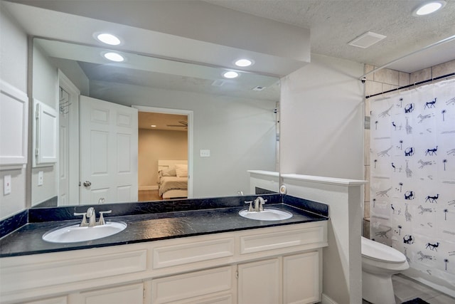 bathroom with a textured ceiling, vanity, and toilet