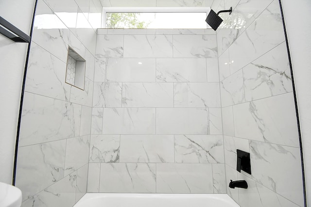 bathroom featuring tiled shower / bath combo and toilet