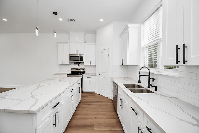 kitchen featuring sink, light stone countertops, decorative light fixtures, white cabinetry, and stainless steel appliances