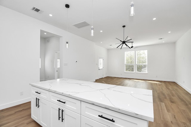 kitchen featuring white cabinets, light stone countertops, decorative light fixtures, and ceiling fan