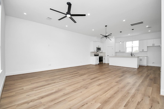 unfurnished living room featuring light wood-type flooring, ceiling fan, and sink