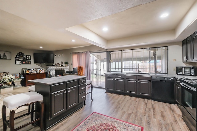 kitchen with sink, light hardwood / wood-style flooring, a kitchen island, and black appliances