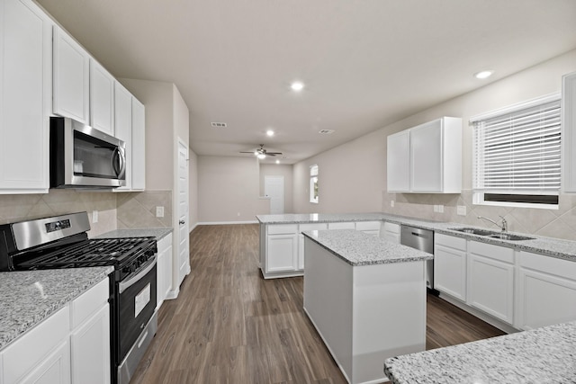 kitchen featuring light stone countertops, white cabinetry, a center island, stainless steel appliances, and sink