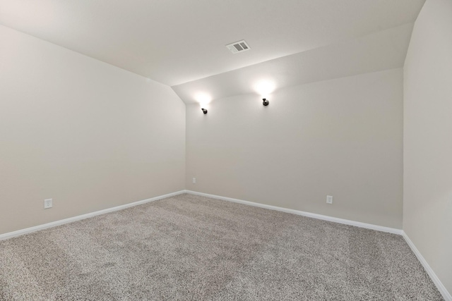 carpeted spare room with vaulted ceiling