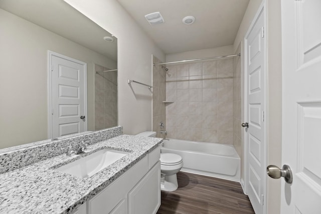 full bathroom featuring tiled shower / bath, hardwood / wood-style floors, vanity, and toilet