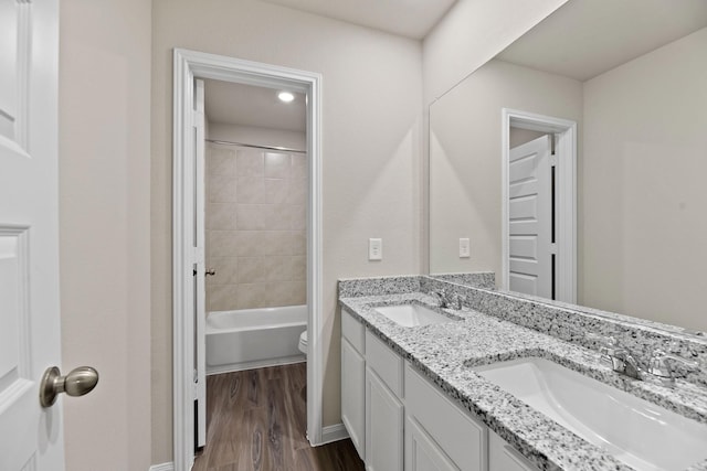 full bathroom with vanity, hardwood / wood-style flooring, toilet, and tiled shower / bath