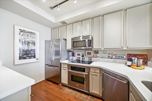 kitchen featuring hardwood / wood-style flooring, rail lighting, and appliances with stainless steel finishes