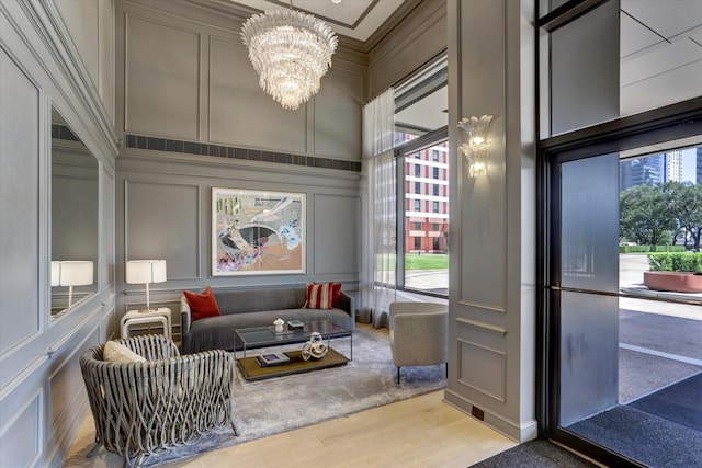 sitting room with a notable chandelier, light hardwood / wood-style floors, crown molding, and a wealth of natural light