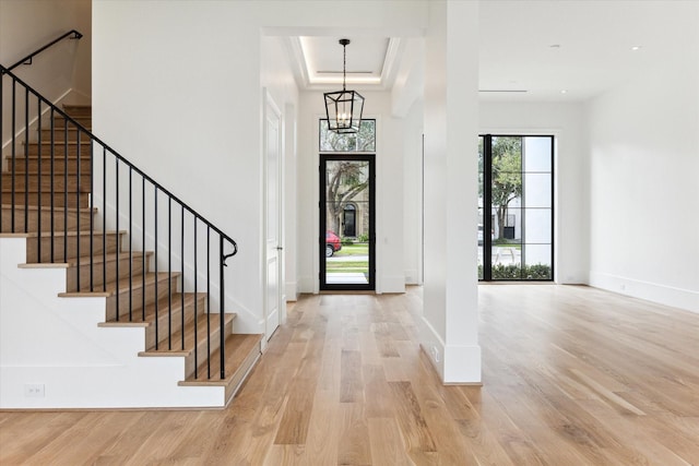 foyer entrance featuring light hardwood / wood-style floors, a tray ceiling, and a notable chandelier