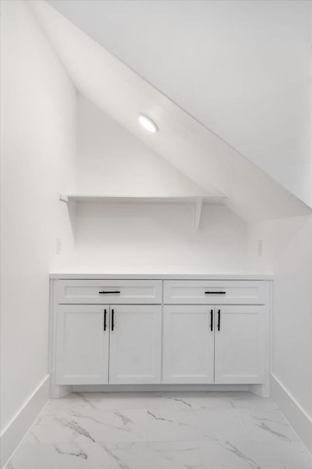 bar with vaulted ceiling, marble finish floor, and baseboards