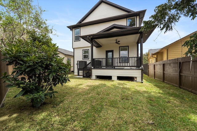 rear view of property with ceiling fan and a lawn