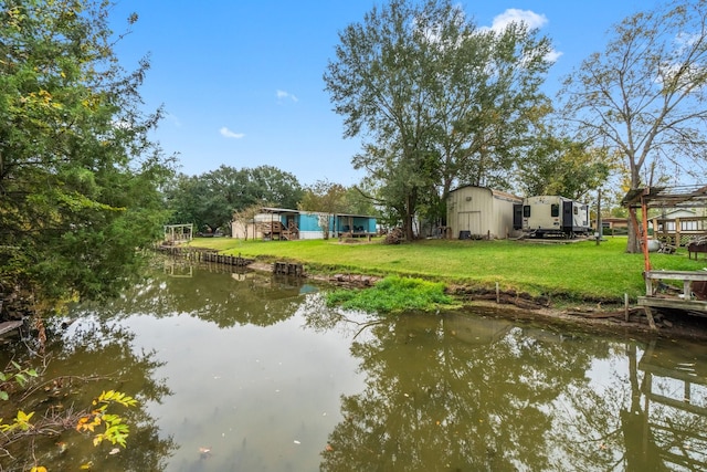 view of dock with a lawn and a water view