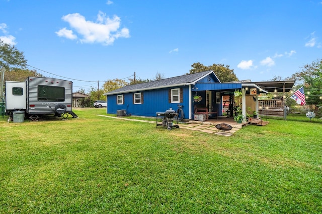 back of house featuring an outdoor fire pit, cooling unit, and a lawn