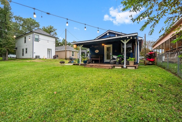 rear view of house featuring a yard, a deck, an outdoor fire pit, and cooling unit