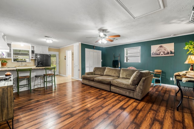 living room featuring ornamental molding, a textured ceiling, ceiling fan, and dark wood-type flooring