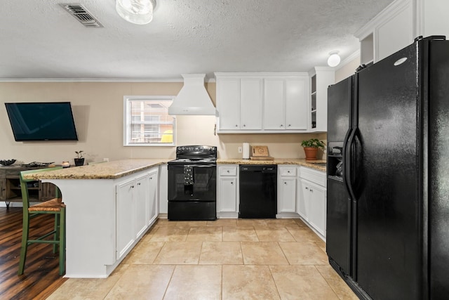 kitchen with a kitchen bar, custom range hood, crown molding, black appliances, and white cabinets