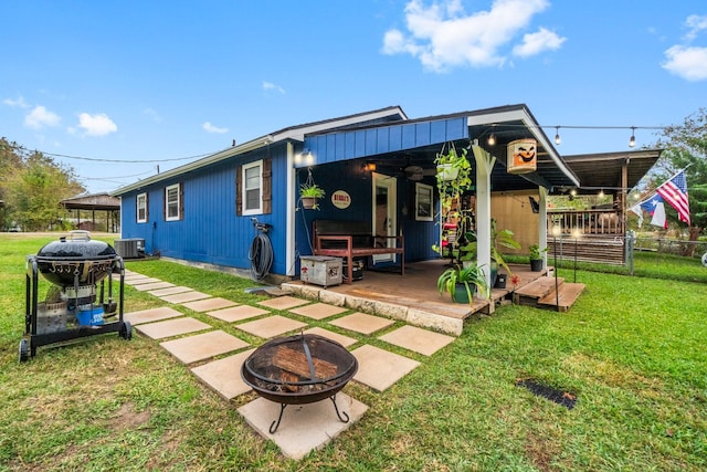 back of house featuring a yard, an outdoor fire pit, cooling unit, and a wooden deck