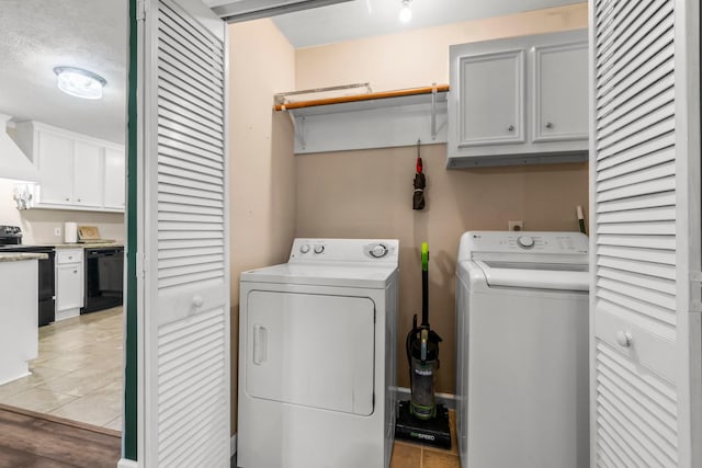 washroom with cabinets, a textured ceiling, light hardwood / wood-style flooring, and washer and clothes dryer