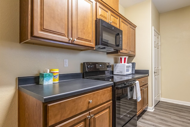 kitchen with hardwood / wood-style flooring and black appliances