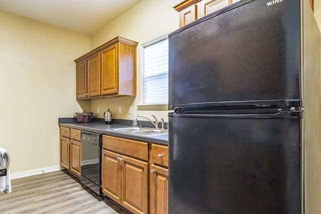 kitchen featuring sink, black appliances, and light hardwood / wood-style flooring