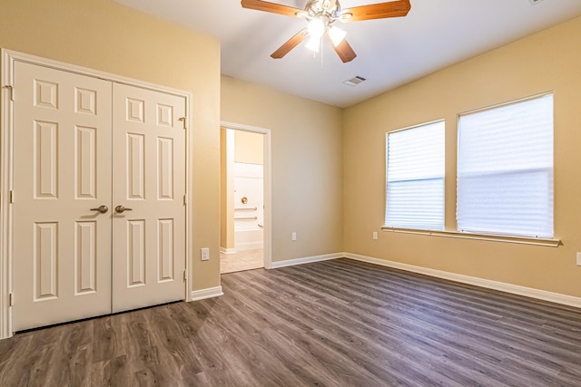 unfurnished bedroom featuring ceiling fan, dark hardwood / wood-style flooring, and a closet