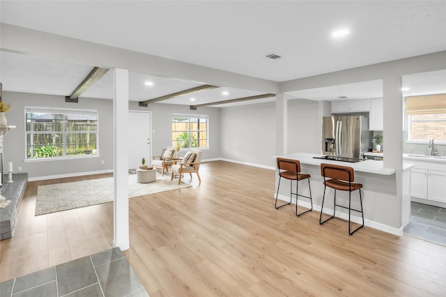 kitchen with white cabinets, stainless steel fridge with ice dispenser, light hardwood / wood-style floors, and plenty of natural light