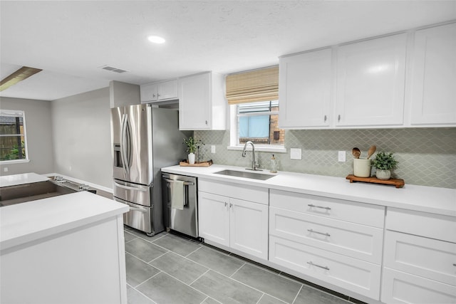 kitchen featuring backsplash, white cabinets, sink, light tile patterned floors, and appliances with stainless steel finishes