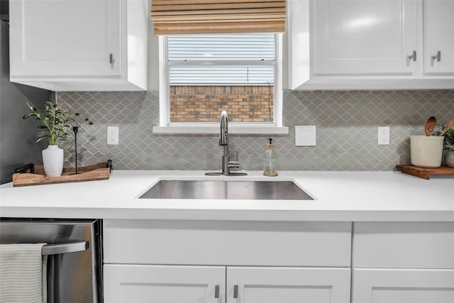 kitchen with tasteful backsplash, white cabinetry, sink, and stainless steel dishwasher