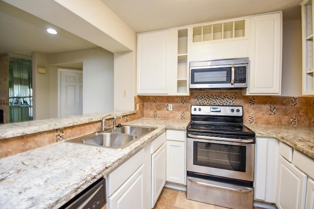 kitchen featuring sink, decorative backsplash, light tile patterned floors, appliances with stainless steel finishes, and white cabinetry