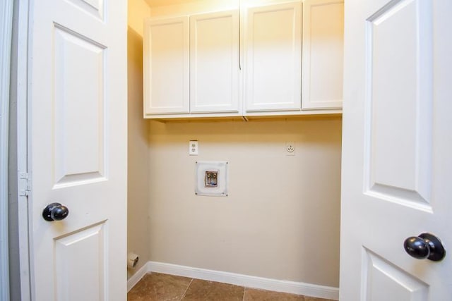 laundry area featuring electric dryer hookup, light tile patterned flooring, and cabinets