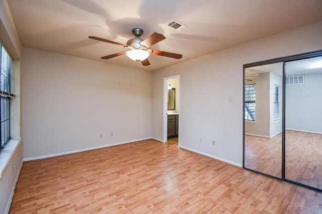 unfurnished bedroom with ensuite bath, light hardwood / wood-style flooring, a closet, and ceiling fan