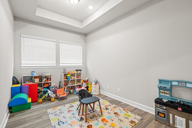 game room with hardwood / wood-style flooring and a tray ceiling