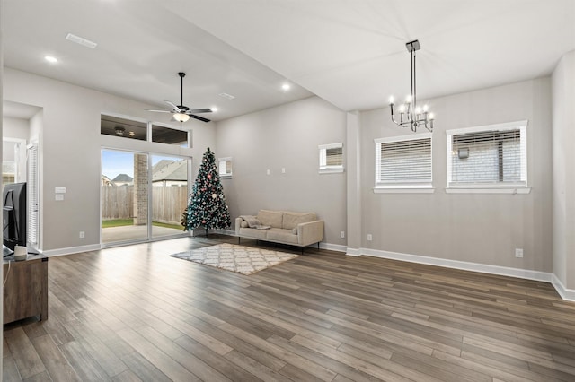 unfurnished room with ceiling fan with notable chandelier and wood-type flooring