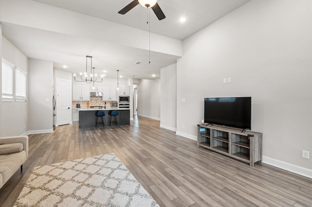 living room featuring light hardwood / wood-style flooring and ceiling fan with notable chandelier