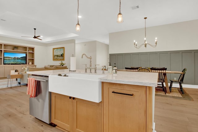 kitchen featuring sink, a center island with sink, dishwasher, light hardwood / wood-style floors, and hanging light fixtures