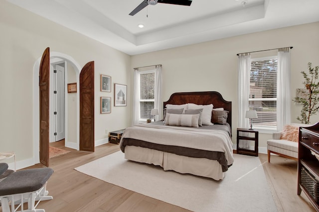 bedroom featuring a tray ceiling, light hardwood / wood-style flooring, and ceiling fan