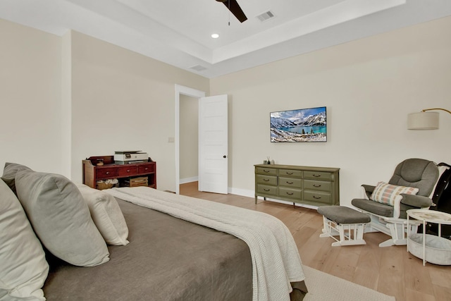 bedroom with wood-type flooring, a tray ceiling, and ceiling fan