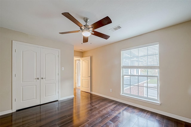 unfurnished bedroom featuring a textured ceiling, ceiling fan, dark wood-type flooring, and a closet